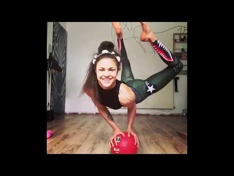 A girl puts glasses on with legs while standing on a ball with hands